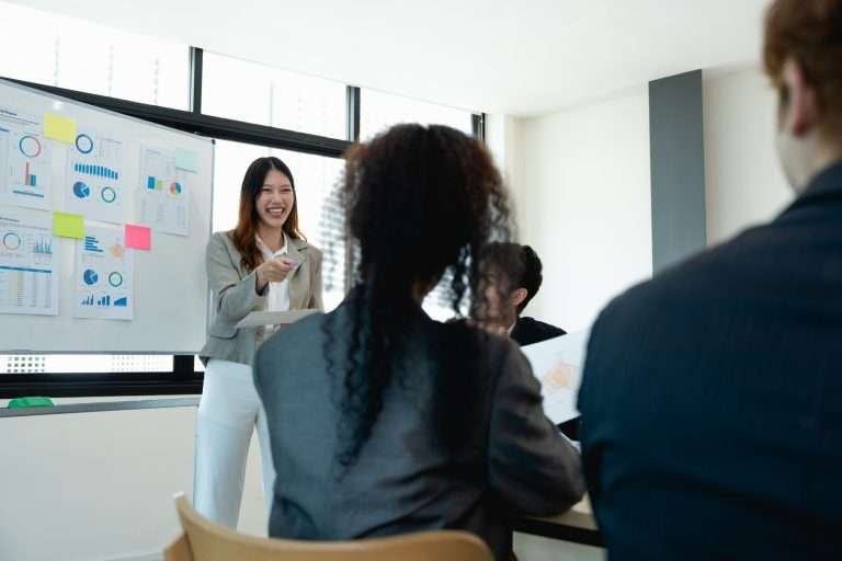 woman supervisor boss teach diverse staff workers explain project plan paperwork at group meeting